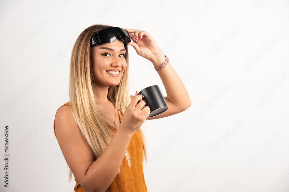 Obraz premium Young woman holding black cup and wearing goggles