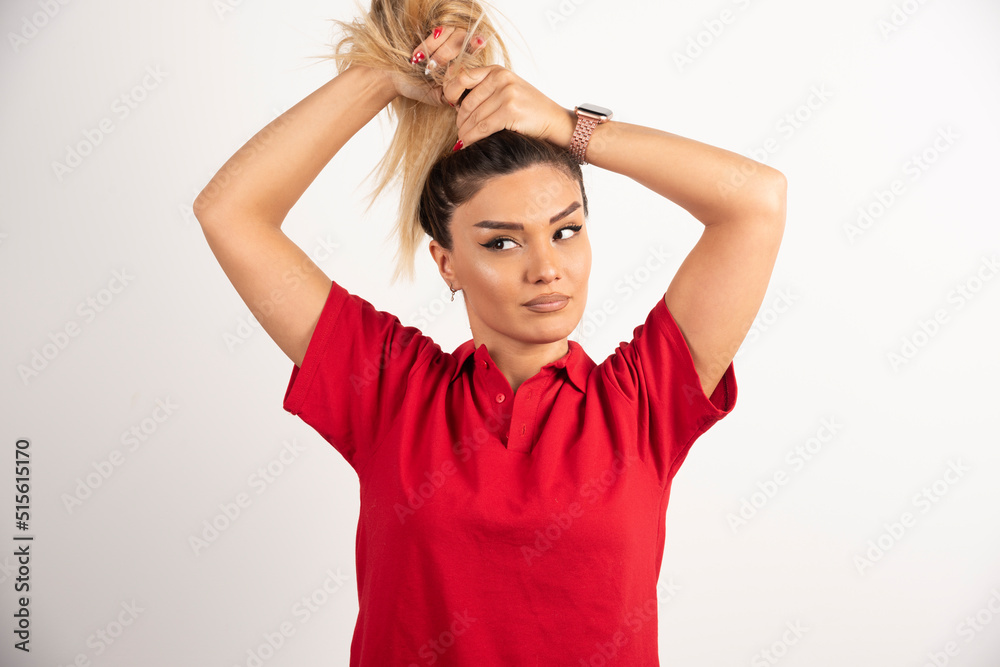 Young woman is doing her hair on white background Young woman is doing her hair on white background