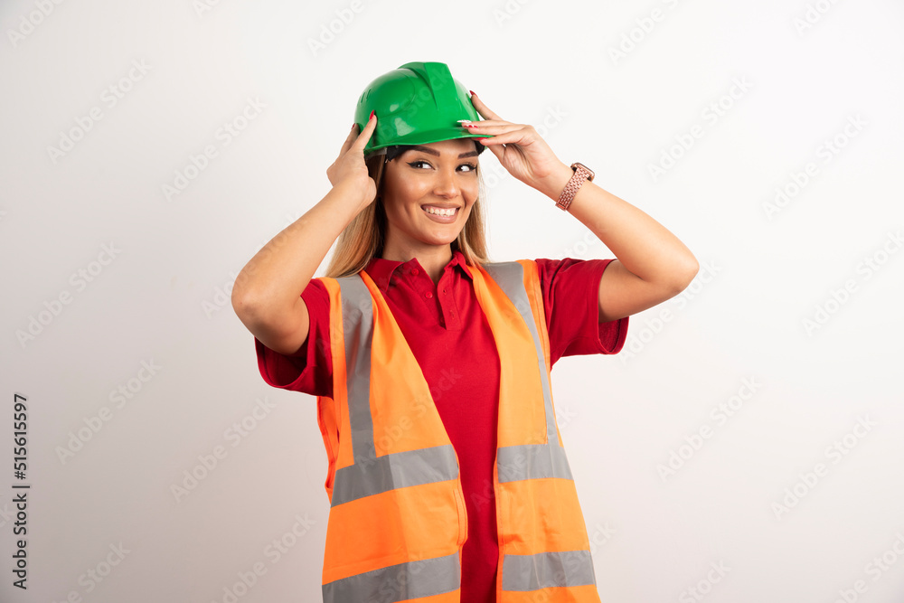 Smiling engineer female wear uniform with hard green helmet on white background