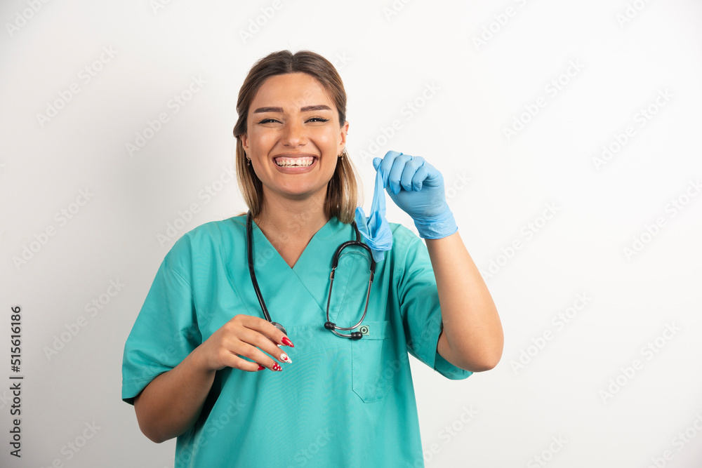 Young woman doctor wearing latex gloves and scrubs on white background Young woman doctor wearing latex gloves and scrubs on white background