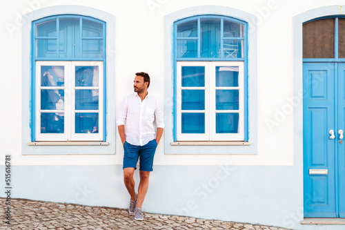 Man standing near white blue building on street