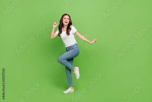 Fototapeta Naklejka Na Ścianę i Meble -  Photo of cute charming woman dressed white t-shirt dancing smiling empty space isolated green color background