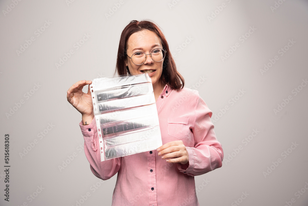Fototapeta premium Young woman holding a photo tape on a white background