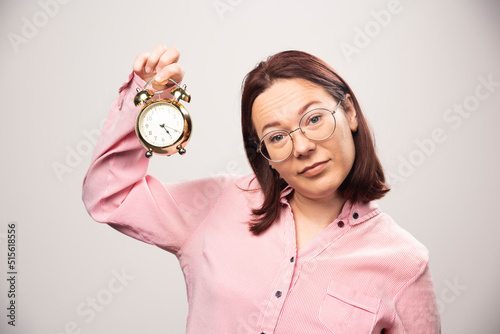 Fototapeta Naklejka Na Ścianę i Meble -  Young woman model holding an alarm clock on a white background