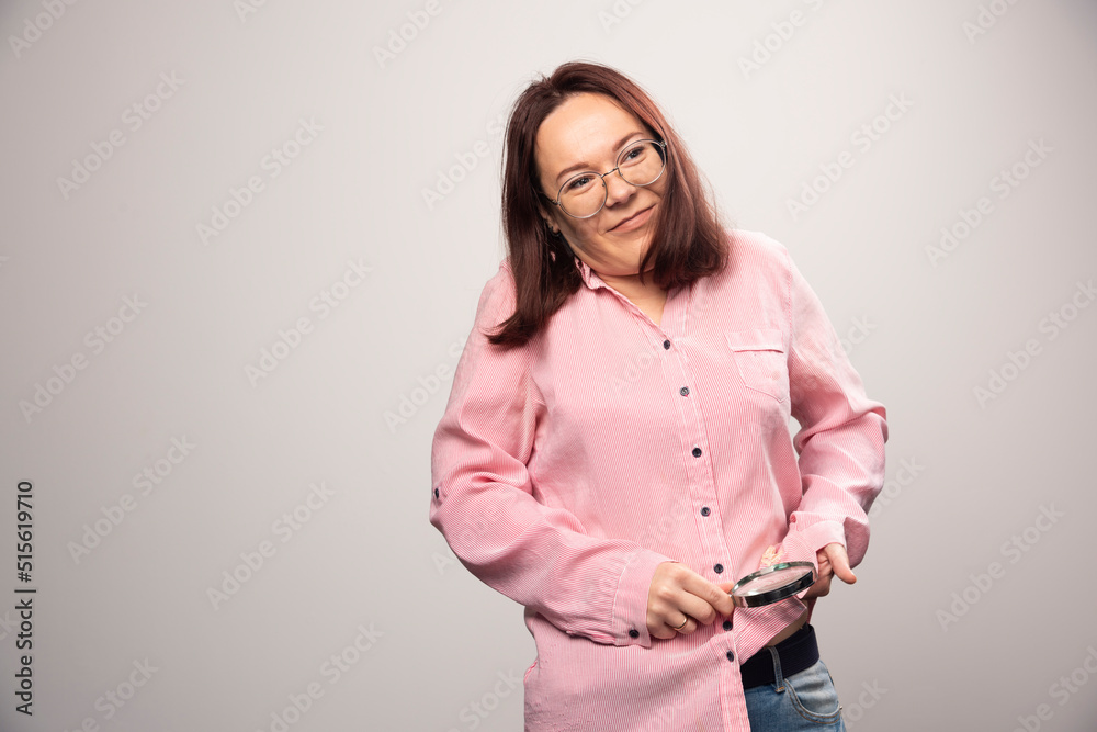 Portrait of woman rubbing a magnifying glass on a white background Portrait of woman rubbing a magnifying glass on a white background