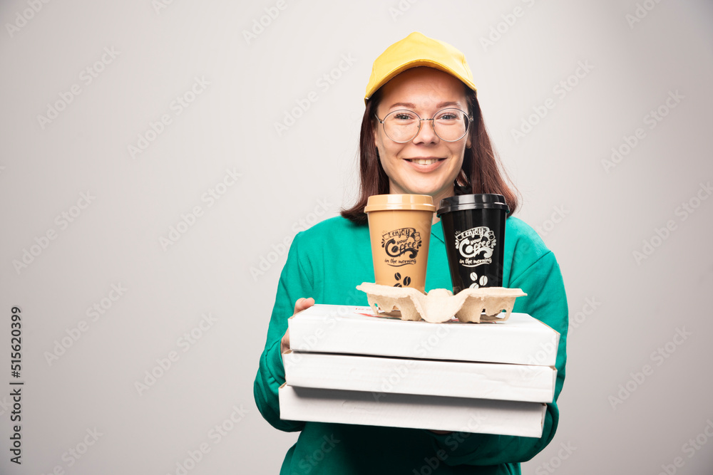 Deliverywoman offering cardboard of coffee cups on a white background Deliverywoman offering cardboard of coffee cups on a white background