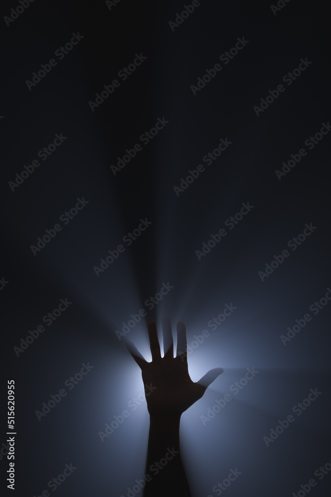 Silhouette of a raised hand in the spotlight.
