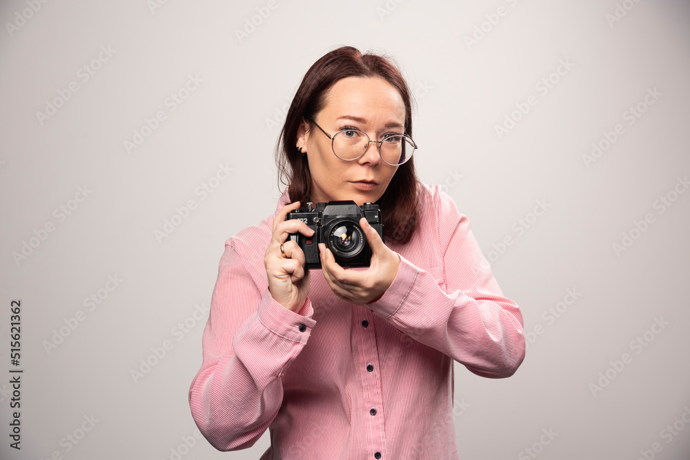 Woman taking a picture with camera on white background