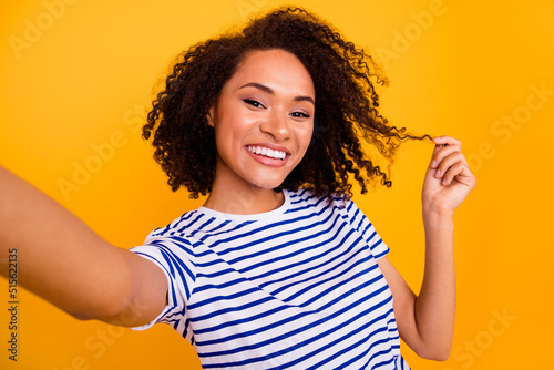 Portrait of cheerful charming lady make selfie hand touch hold hairdo curl isolated on yellow color background © deagreez