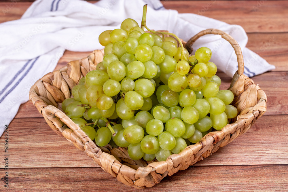 Fresh green grapes. Ripe grapes in basket on wood background. Bulk grapes. close up Fresh green grapes. Ripe grapes in basket on wood background. Bulk grapes. close up