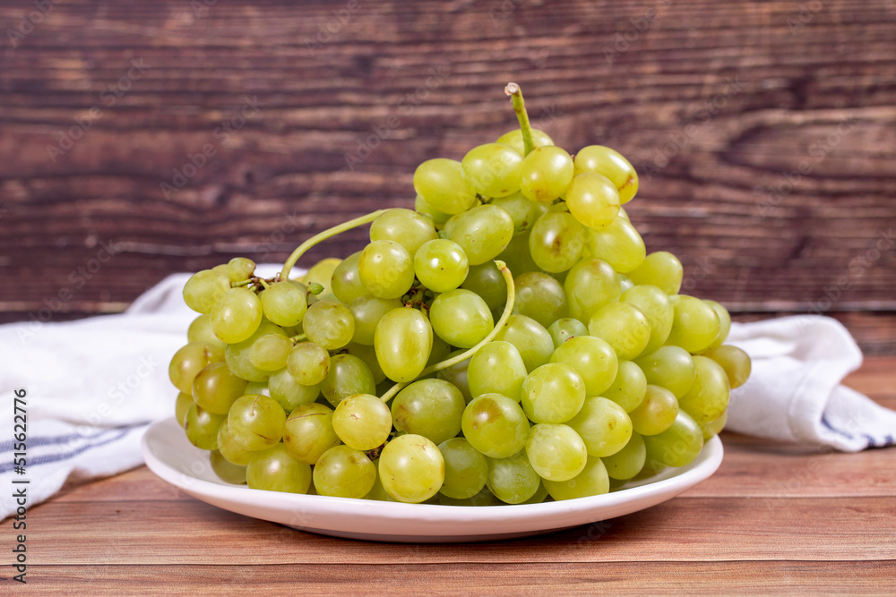 Fresh green grapes. Ripe grapes in plate on wood background. Bulk grapes. close up Fresh green grapes. Ripe grapes in plate on wood background. Bulk grapes. close up