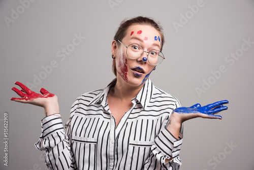 Woman posing with paints on her face on gray background