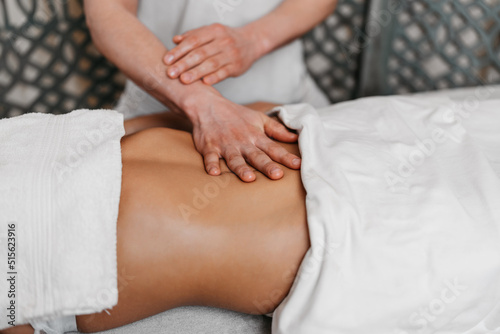 Beautiful young woman receiving professional body massage treatment with aromatherapy essential oil.