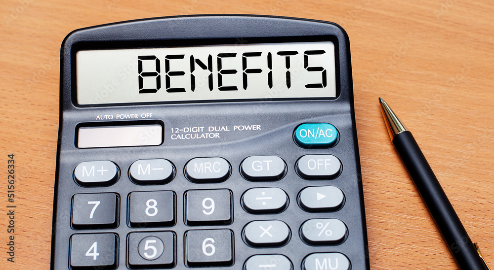 On a wooden table there is a black pen and a calculator with the text BENEFITS. Business concept On a wooden table there is a black pen and a calculator with the text BENEFITS. Business concept