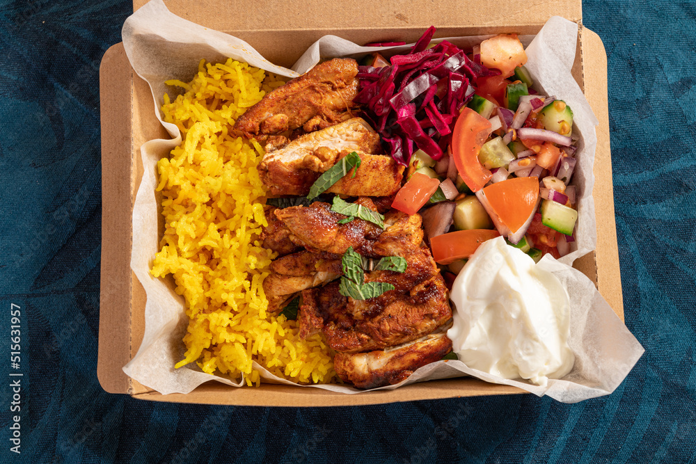 Traditional Eastern Mediterranean takeaway meal of grilled chicken, yellow rice, fresh salad and yoghurt in cardboard - obrazy, fototapety, plakaty 