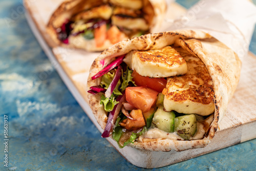 Traditional Mediterranean Arabic grilled halloumi, hummus and vegetables in flatbread wraps topped with herbs and balsamic vinegar