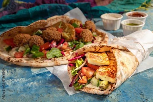 Traditional Mediterranean Arabic grilled halloumi and falafel, hummus and vegetables in flatbread wraps with herbs and sauces