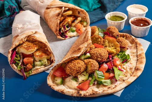 Traditional Mediterranean Arabic grilled halloumi and falafel, hummus and vegetables in flatbread wraps with herbs and sauces