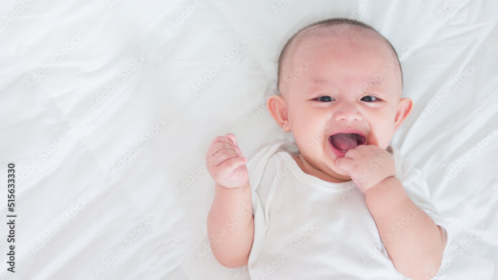 Portrait of cute asian newborn baby lying play on white bed look at camera with laughing smile happy face. Innocent little new infant adorable. Parenthood and Mother Day concept. Portrait of cute asian newborn baby lying play on white bed look at camera with laughing smile happy face. Innocent little new infant adorable. Parenthood and Mother Day concept.