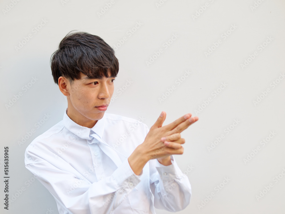 Portrait of Chinese young man with black hair in white shirt posing against white background, hand out with shoot gun gesture, aim at you concept, front view. Portrait of Chinese young man with black hair in white shirt posing against white background, hand out with shoot gun gesture, aim at you concept, front view.