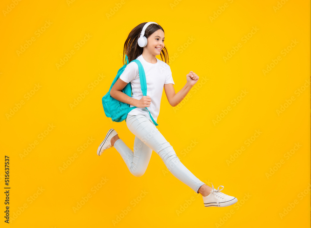 Happy teenager portrait. School teenager child girl in headphones with school backpack. Teenager student, isolated background. Learning music. Jump and run, jumping child.