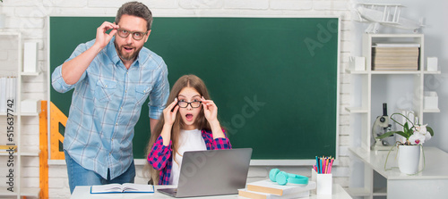 Father and daughter at school, teacher and pupil banner. surprised dad and daughter near clackboard. back to school. childhood education. photo