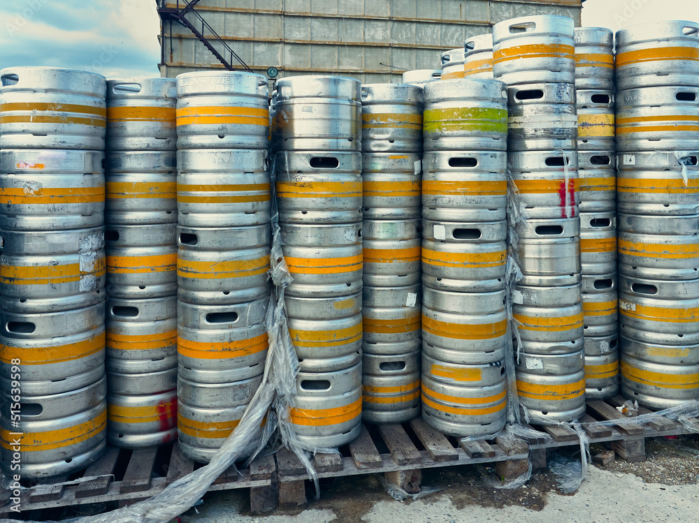 Old used beer kegs are stacked on pallets, barrels are whole and can