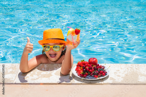Child drink cocktail. Summer child by the pool eating fruit and drinking lemonade cocktail. Summer kids vacation concept. Little kid boy relaxing in a pool having fun during summer vacation.