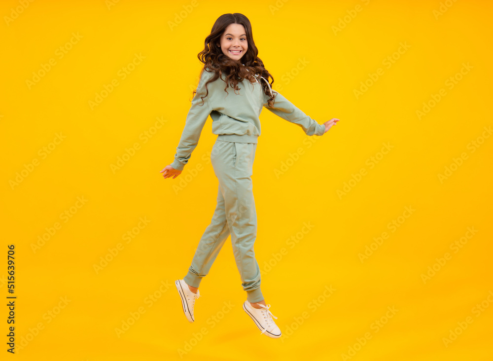Sports studio kids portrait. Cute teenager girl in a purple casual sports suit. Child in a stylish sports suit on yellow background isolated.