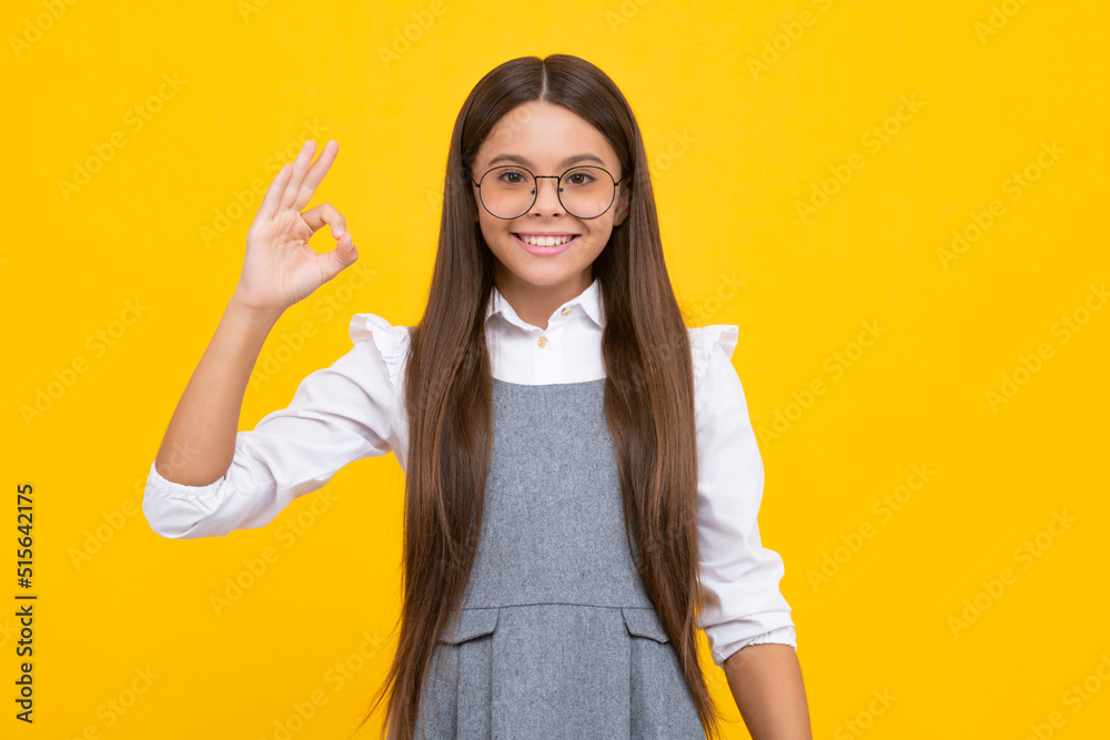 Portrait of a little teenager child girl showing okay gesture isolated over yellow background. Ok sign concept. Happy girl face, positive and smiling emotions. Portrait of a little teenager child girl showing okay gesture isolated over yellow background. Ok sign concept. Happy girl face, positive and smiling emotions.