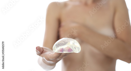 Woman holds silicone breast implant for breast augmentation