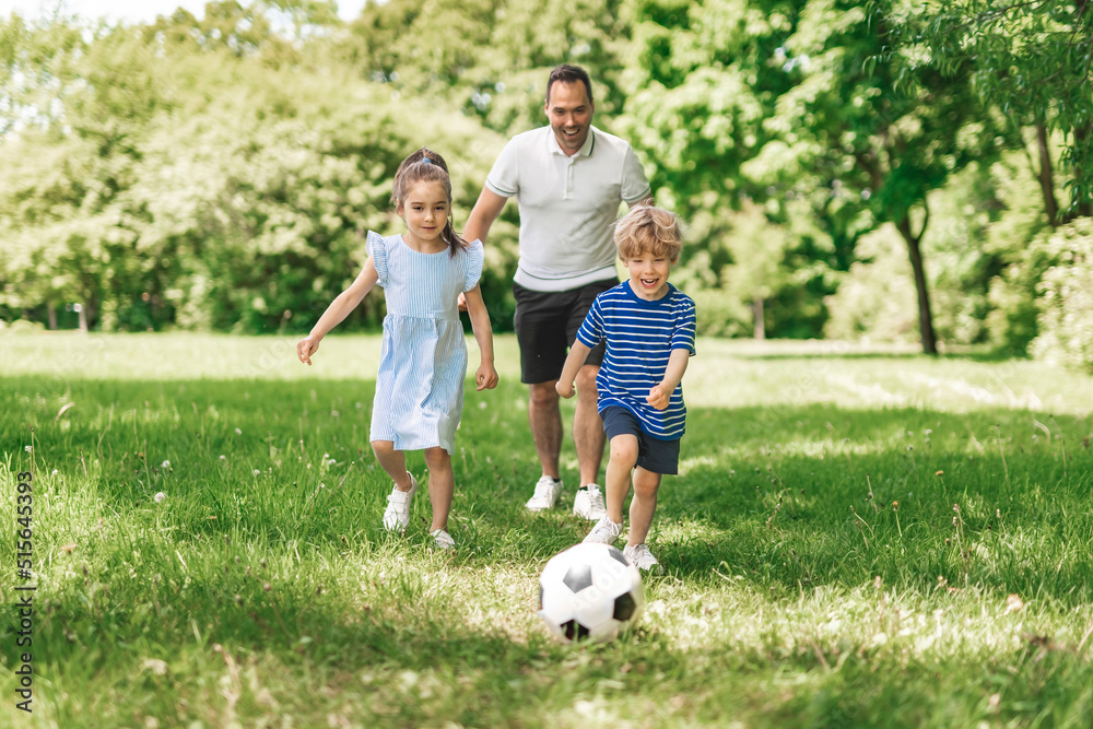 Handsome dad with his child playing football on green grassy lawn Handsome dad with his child playing football on green grassy lawn