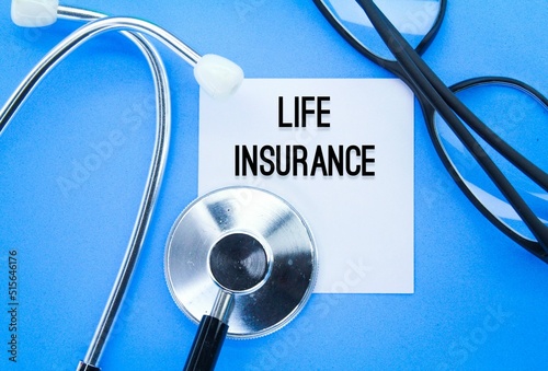 stethoscope, glasses and white paper with the word life insurance. the concept of health insurance photo