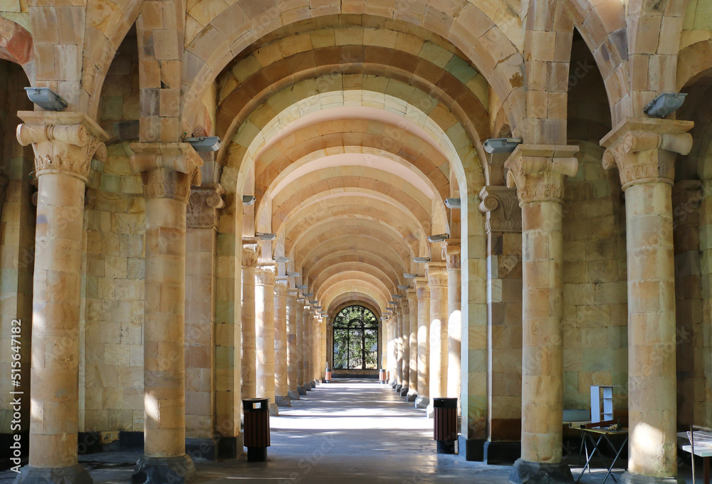 Gallery of columns and arches in a public park, built of light stone, ending with a window, horizontal