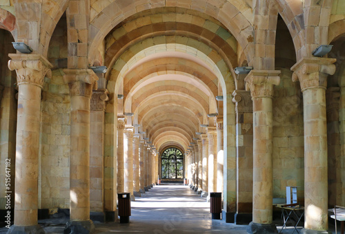 Gallery of columns and arches in a public park  built of light stone  ending with a window  horizontal