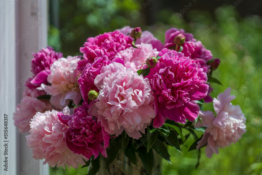 Beautiful bouquet of pink peonies flowers in a glass vase on the windowsill at home, close-up Beautiful bouquet of pink peonies flowers in a glass vase on the windowsill at home, close-up