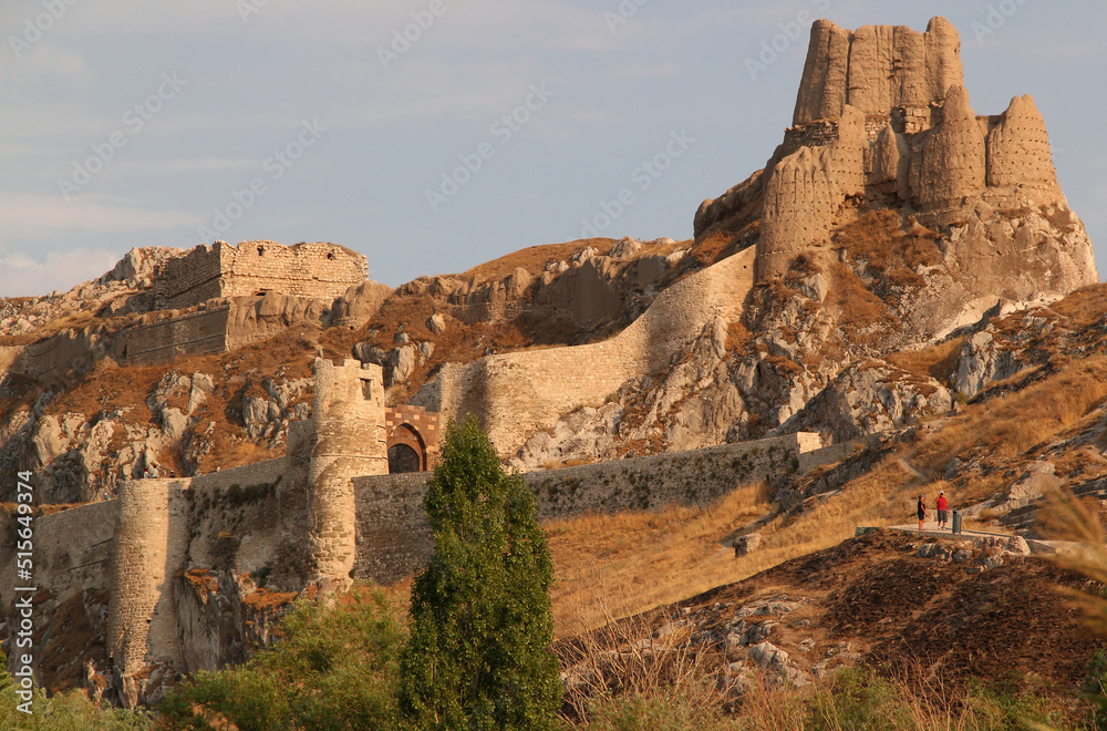 View of the old part of Van Castle, which is located on a high rock, with an entrance gate, against a blue sky with clouds, in the Eastern Anatolia region, Turkey