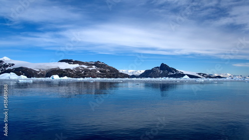 Icebergs floating at the base of a snow covered mountain, in the Southern Ocean, at Cierva Cove, Antarctica