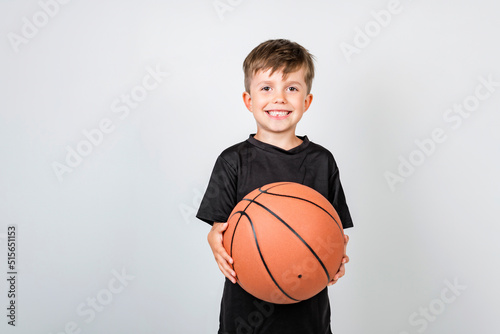 Portrait of smiling little boy with basketball ball over grey background