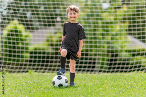 Cute boy playing football enjoying sport game outside © pololia