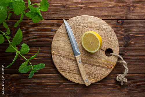 Fototapeta Naklejka Na Ścianę i Meble -  Lemon with knife on cutting board on wooden background.