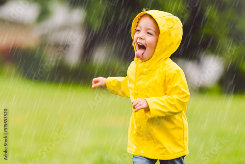 Fotografie Happy funny child with raincoat under the summer raining day