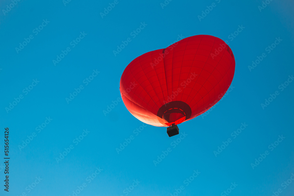 Hot air balloon in the shape of a red heart in the blue sky - the concept of love, hope and freedom Hot air balloon in the shape of a red heart in the blue sky - the concept of love, hope and freedom