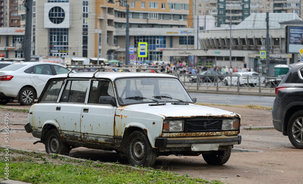 An old white rusty car is parked on the street, Bolshevikov Avenue, St. Petersburg, Russia, July 2022