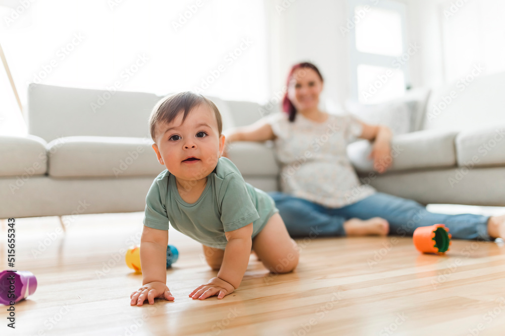 Mother and the Cute 8 month baby laying on floor, playing with toys Mother and the Cute 8 month baby laying on floor, playing with toys