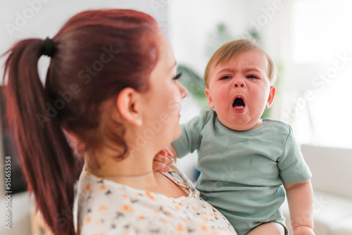 mother holding child baby on the living room. The baby is sick having some cough