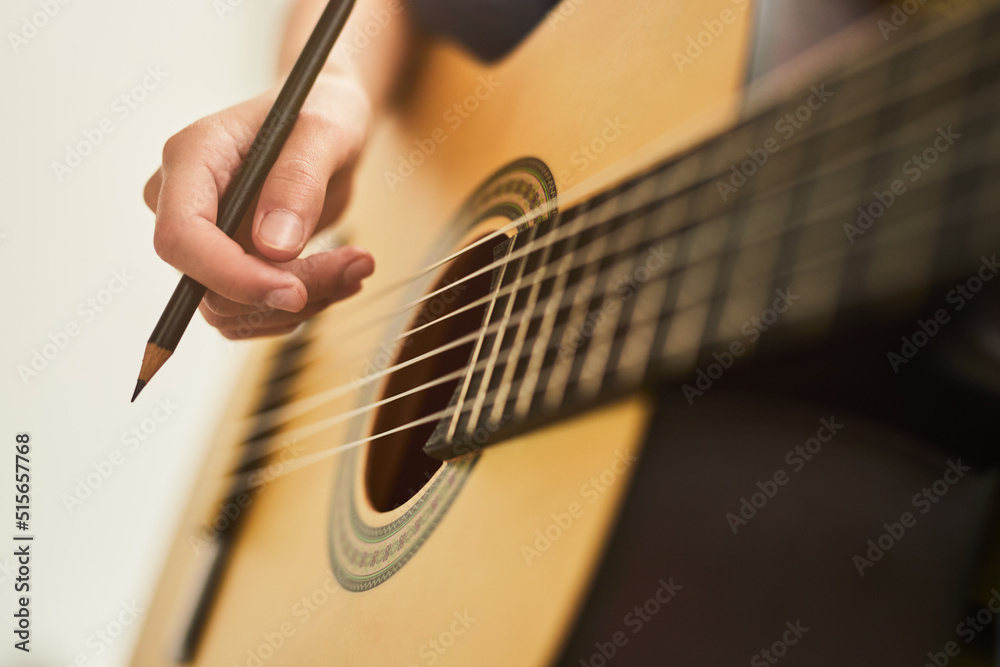 Fototapeta premium Crop musician with pencil playing guitar