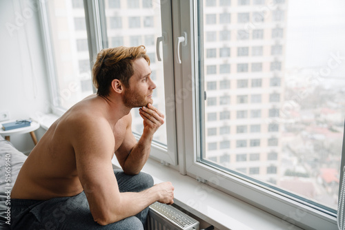 Young white shirtless man sitting in thoughtful position at home Free Download Young white shirtless man sitting in thoughtful position at home - GFXLoad