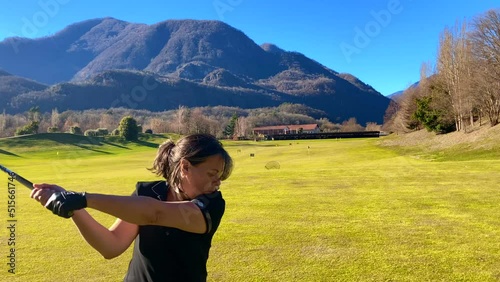 Golfer Training with Her Golf Club Driver in Driving Range with Mountain View in a Sunny Day in Losone, Ticino, Switzerland. photo