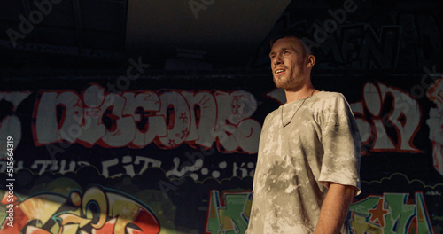 Smiling teenager roller skating at skatepark with graffiti wall background. 